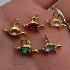 Five colorful turtle pendants with marquise-cut gems on gold plating shown in hand