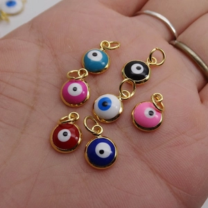 Colorful enamel evil eye charms in gold plated alloy shown in hand for DIY jewelry making