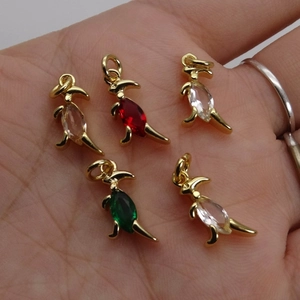 Detailed close-up of small gold dinosaur charms with multicolor zircon stones on palm