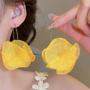 Close-up detail of yellow chiffon flower earrings with lightweight fabric petals and gold hooks