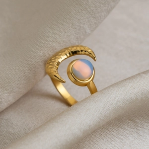Close-up of a 18K gold-plated stainless steel crescent moon ring with a round opal stone.