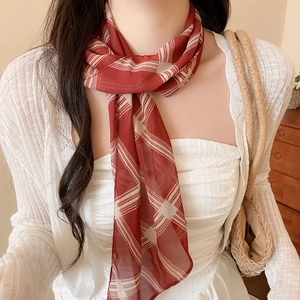 Detailed macro shot of a lightweight red plaid mesh silk scarf worn as a stylish necktie