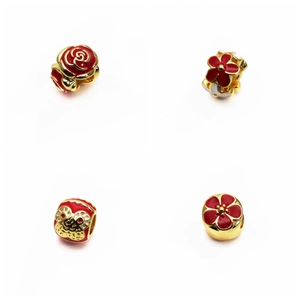 Detailed view of four gold charms with red enamel floral and traditional patterns