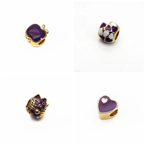 Dettaglio di quattro charm in smalto viola e oro con design a gatto portafortuna e cuore
