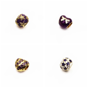 Dettaglio macro di charm in smalto viola con stelle marine dorate e motivi a cuore