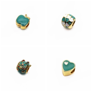 Détail des charms en émail vert et plaqué or avec motifs de chat porte-bonheur et pomme