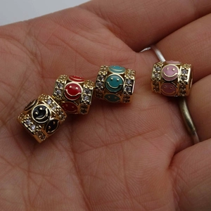 Detailed view of 14K gold plated smiley face beads with cubic zirconia and enamel on palm