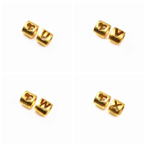Détail de perles alphabet et cœur dorées avec gravure 999 et finition mate élégante