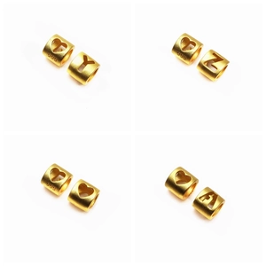 Vue macro de perles plaquées or 999 avec découpes alphabétiques et finition mate sablée