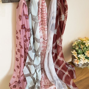 Close-up of various Korean style floral and grid mesh scarves hanging vertically