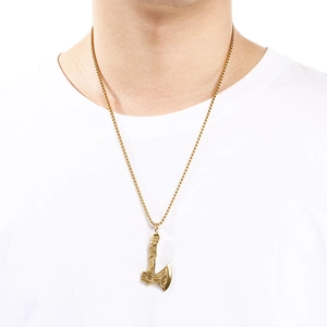 Close-up of a vintage Viking axe pendant on a gold chain worn by a male model.