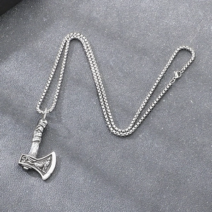 Close-up of Nordic Viking battle axe pendant with intricate wolf totem engraving.