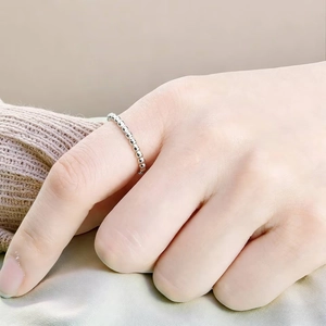 Close-up of a minimalist 2mm silver beaded stainless steel ring on a woman's hand.