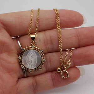 Dettaglio della collana dorata con ciondolo della Vergine Maria e intarsio in madreperla