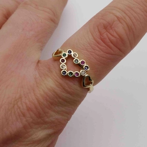 Vue détaillée d'une bague coeur ajustable sertie de zircons colorés portée au doigt