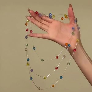 Détail d'un collier multicouche avec des perles facettées colorées sur chaîne argent