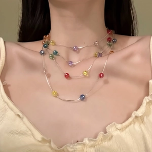 Vue détaillée d'un collier ras du cou multicouche à perles colorées porté par un modèle