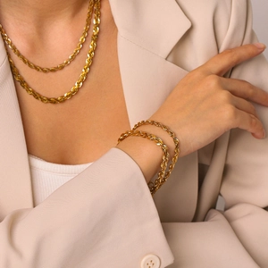 Vue détaillée du collier et du bracelet chaîne en or 18 carats sur modèle en acier inoxydable