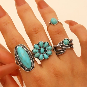 Detail of vintage bohemian silver ring set featuring turquoise and floral motifs on hand