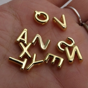 Polished 14K gold-plated alphabet letter beads for DIY jewelry making in a hand palm