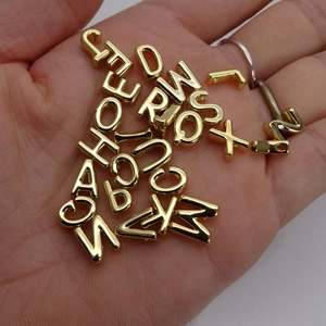 14K gold-plated A-Z alphabet charms for DIY jewelry making held in hand for scale