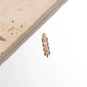Macro di un ciondolo a barra in acciaio inossidabile dorato con quattro strass rosa.