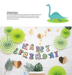 Detail of dinosaur birthday banner with green paper fans and gold stars on white wall
