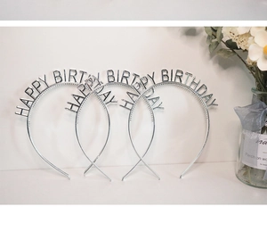 Close-up of three silver Happy Birthday headbands with metallic finish on a white table