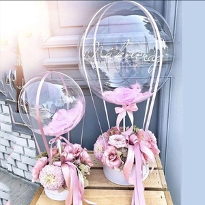 Close-up of decorative transparent balloons with pink feathers and floral box base decor
