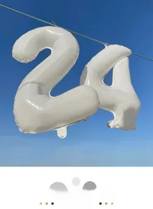 Outdoor view of 40 inch cream white foil number balloons 2 and 4 against blue sky