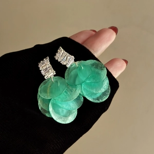 Dettaglio di orecchini a nappa in conchiglia verde con borchie di zircone lucido