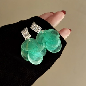 Dettaglio di orecchini a frangia in conchiglia verde con perni in zircone