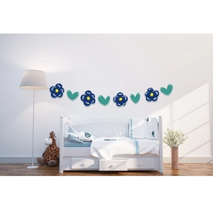 Guirlande fleurs bleues et cœurs verts sur un mur blanc au-dessus d'un lit d'enfant