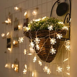 Detail of warm white snowflake LED string lights on wicker basket and green plants