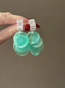 Primo piano di orecchini di conchiglia verde menta con borchie in zircone