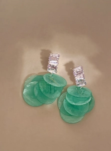 Primo piano di eleganti orecchini in conchiglia verde e zircone su sfondo neutro