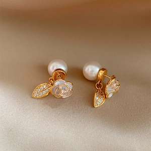 Elegant camellia pearl stud earrings with sparkling zircon leaf detail on beige fabric