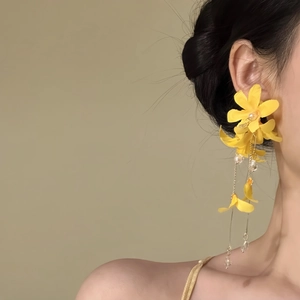 Detailed macro view of yellow fabric flower tassel earrings perfect for beach holiday style