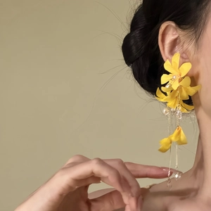 Close-up detail of vibrant yellow flower tassel earrings on model for a vacation look