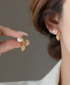 Detail of elegant camellia earrings with pearls and zircon leaf charms on gold finish
