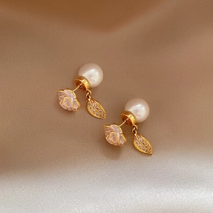 Macro detail of camellia flower and pearl stud earrings with zircon leaf charms.