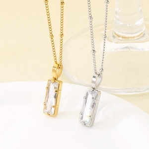Gros plan de colliers en acier inoxydable or et argent avec pendentifs en cristal rectangle.