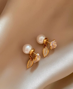 Detailed view showing the elegant camellia flower and pearl design of these gold earrings.