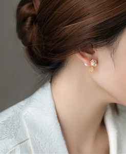 Detailed close-up showing elegant camellia pearl earrings with zircon leaf on female ear