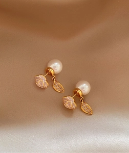 Macro view of elegant camellia flower and pearl drop earrings with sparkling zircon leaf