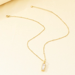 Vue rapprochée du pendentif en cristal rectangulaire sur une chaîne en acier doré.