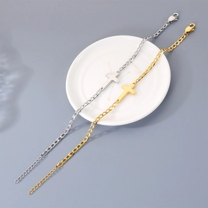 Close-up of gold and silver stainless steel cross bracelets on a white ceramic plate.