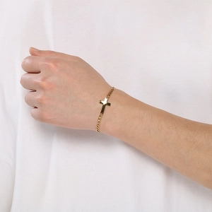 Detail showing a minimalist gold-plated stainless steel cross chain bracelet on a wrist