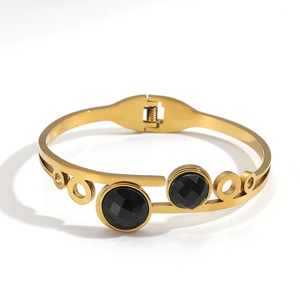 Macro detail view of a gold titanium steel bangle with two faceted black circular stones