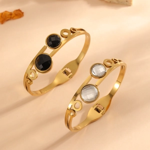 Close-up of gold stainless steel bangles with black and clear round rhinestone inlays